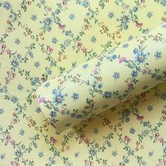 a rolled up roll of toilet paper on top of a flowered tablecloth with blue and pink flowers