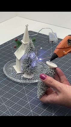 a person is making a miniature christmas tree out of tinsel and plastic beads with a blow dryer