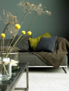 a living room with a couch, coffee table and flowers in vases on the floor