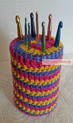 a crocheted container with many pins sticking out of it