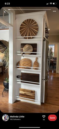 a kitchen with white shelves and wooden cutting boards on top of them in front of a staircase