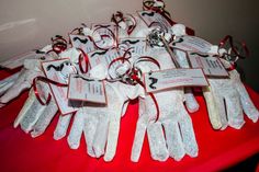 many white gloves with tags attached to them sitting on a red cloth covered tablecloth