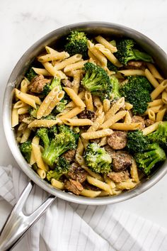 a pan filled with pasta and broccoli on top of a white tablecloth