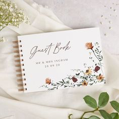 a wedding guest book with flowers and greenery