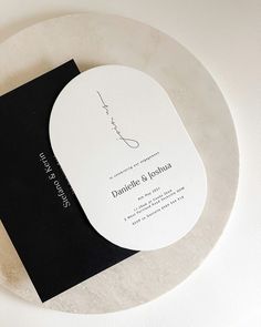 a black and white wedding card on top of a circular plate with the name danielle & joshua printed on it