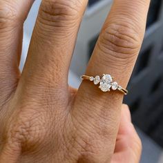 a woman's hand with a three stone diamond ring on her left and right hand