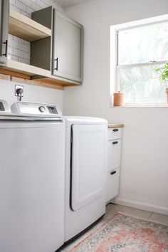 a white washer and dryer sitting in a kitchen next to a window with potted plants