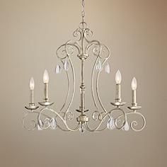 a white chandelier hanging from a ceiling in a room with beige walls and flooring