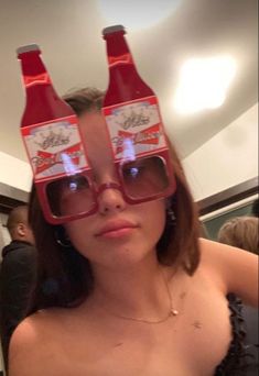 a woman wearing glasses with coca - cola bottles on her head, and another person in the background