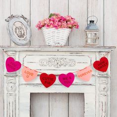 a white fireplace with pink and red hearts hanging from it