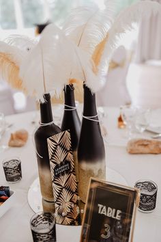 there are three bottles on the table with some feathers in them and an empty menu