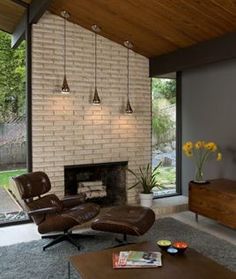 a living room with a couch, chair and television on the wall in front of a brick fireplace