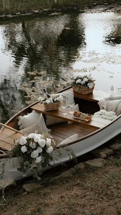 a small boat with flowers on the front is sitting in the grass near some water