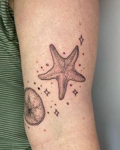 a starfish and sea urchin tattoo on the right arm, with stars in the background