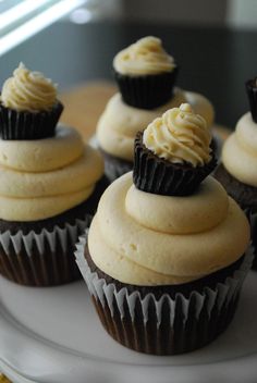 several cupcakes with white frosting on a plate