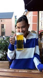 a woman sitting at a table with a beer in her hand