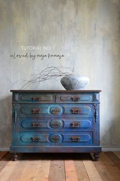 an old blue dresser with a vase on top