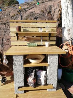 an outdoor kitchen made out of pallet wood and concrete with potted plants in the background