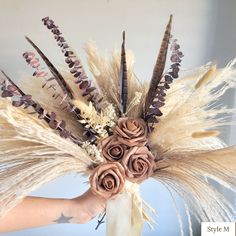 a person holding flowers in their hand with feathers on the top and bottom of it