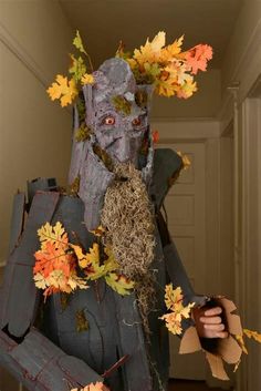 a man dressed up as a scarecrow with autumn leaves around his neck