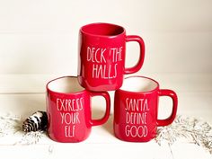 three red coffee mugs with words on them sitting next to a zebra's tail