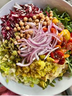 a salad with red onions, lettuce, tomatoes and chickpeas in it