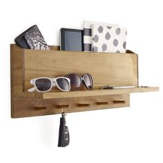 a wooden shelf with sunglasses and other items on top of it, hanging from the wall