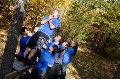 a group of people standing on top of a wooden platform in the woods with trees