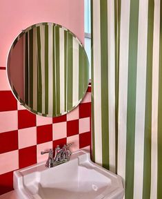 a white sink sitting under a bathroom mirror next to a green and red checkered shower curtain