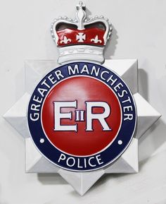 the emblem for greater manchester police is shown on a white wall with blue and red accents