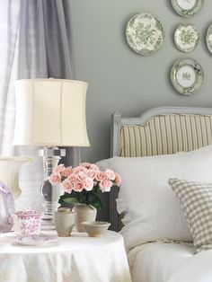 a white bed topped with lots of pillows next to a table covered in plates and flowers