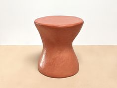 a small brown vase sitting on top of a table next to a white wall and floor