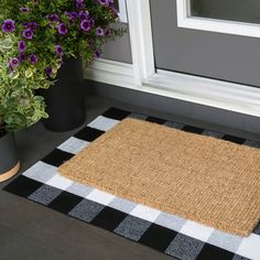 a black and white checkered door mat next to purple flowers