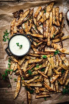 french fries with ranch dressing on a piece of parchment paper next to a bowl of ranch dressing