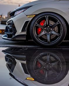 the front end of a white sports car with red brake lights and black rims