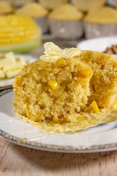 a muffin with white frosting on a plate next to other muffins