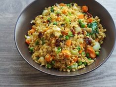 a bowl filled with rice and vegetables on top of a wooden table