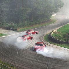 three cars driving on a race track in the rain