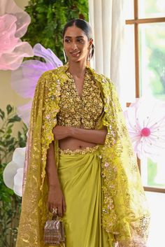 Shine bright like a diamond at this season’s soirees. The lime green set comes with a blouse covered with daisy flower applique work. The dhoti-style skirt also glamourizes the outfit with its asymmetrical look. The Dupatta/cape that is paired with the outfit has an ombre effect to tie in all the colors of the embellishments. Blouse comes with a V-neck along with hook in the front accentuated with daisy intricacies all over. A ombre cape made out of cutwork at the border entices the outfit. Drap Green Embellished Pre-draped Saree For Wedding, Green Pre-draped Saree With Dupatta For Party, Pista Green Pre-draped Saree With Sheer Dupatta For Party, Yellow Pre-draped Saree For Party, Yellow Pre-draped Saree With Gota Work For Party, Green Blouse With Sheer Dupatta For Wedding, Party Green Choli With Dori Work, Green Wedding Blouse With Sheer Dupatta, Festive Pista Green Pre-draped Saree For Party