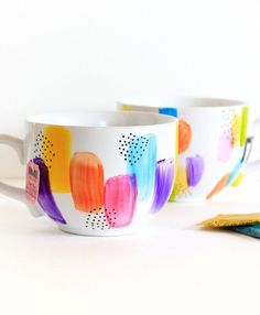 two coffee mugs with colorful designs on them