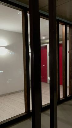 an empty room with red doors and white walls is seen through the glass door frames