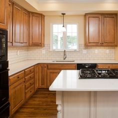 a large kitchen with wooden cabinets and white counter tops, along with an island in the middle