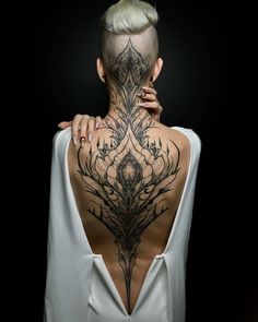 the back of a woman's neck with tattoos on it and an intricate design