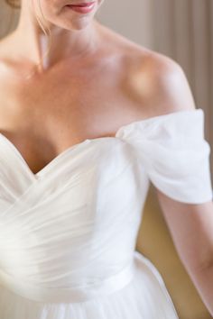 a woman in a white dress is looking down at her wedding ring on her finger