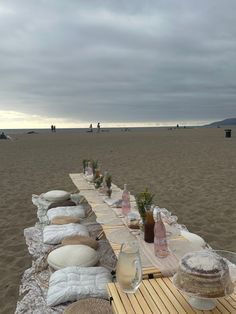 a long table set up on the beach with food and drinks in front of it