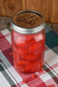 red hot cinnamon apples in a mason jar on a checkered tablecloth with text overlay