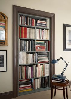 a bookshelf filled with lots of books next to a lamp