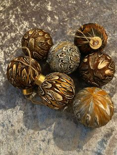 five decorative ornaments sitting on top of a gray cloth covered tablecloth with gold accents