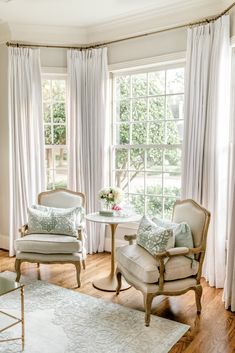 a living room filled with furniture and windows covered in white draping next to a wooden floor