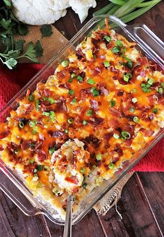 a casserole dish with meat and vegetables in it on a table next to cauliflower